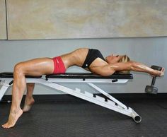 a woman laying on top of a bench in a gym