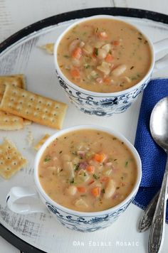 two bowls of soup and crackers on a plate