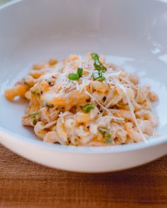 a white bowl filled with macaroni and cheese on top of a wooden table