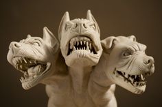 three statues of dogs with their mouths open and teeth wide opened, all facing different directions