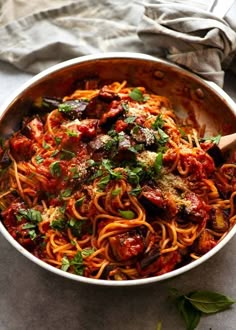 a pan filled with pasta and sauce on top of a table next to a wooden spoon