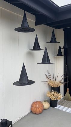 a group of black hats hanging from the side of a building next to pumpkins