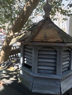 an old wooden gazebo sitting next to a tree