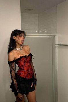 a woman in a red and black corset posing for the camera with her hands on her hips