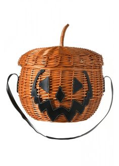 a wicker basket with a carved pumpkin on it's side and black handles