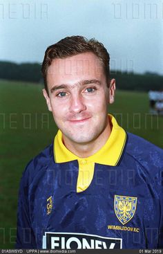 a young man in a blue and yellow soccer uniform posing for a photo on the field