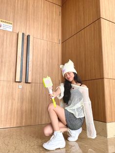 a woman sitting on the floor with a toothbrush in her hand and wearing a white hat