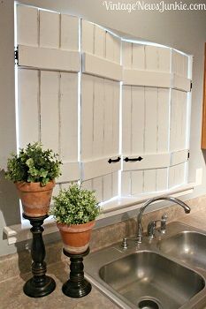 two potted plants sitting on top of a kitchen counter next to a metal sink