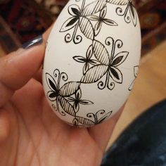 a hand holding an egg decorated with black and white designs on it's shell