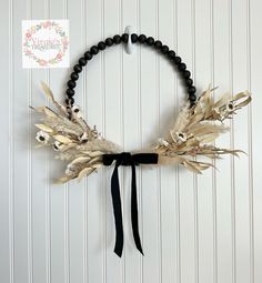 a black beaded headband with dried flowers and leaves on it, hanging from a wall