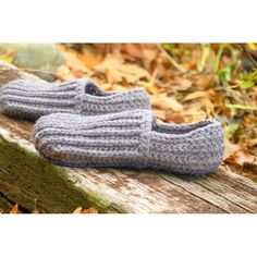 a pair of crocheted slippers sitting on top of a wooden bench in the woods