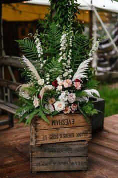 a wooden crate with flowers and greenery in it