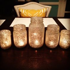 five lit candles sitting on top of a wooden table next to a pillow and pillows