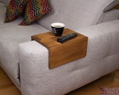 a couch with a remote control and a cup of coffee sitting on top of it