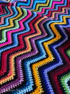 a colorful crocheted blanket is laying on the floor