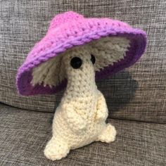 a crocheted dog wearing a pink and purple hat on top of a couch