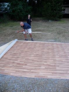 a man standing on top of a wooden floor in the middle of a yard next to another man