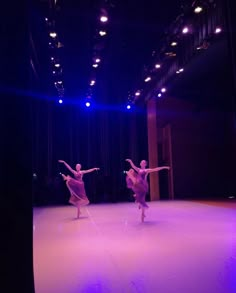 two dancers are performing on stage in front of purple lights and blue lighting from the ceiling