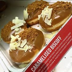 three chocolate covered doughnuts in a box on a counter top with cinnamon sprinkles