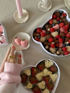 two heart shaped bowls filled with strawberries, chocolates and raspberries in them