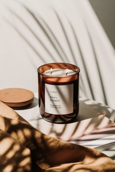 a candle sitting on top of a table next to a wooden plate with a shadow