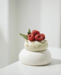 a white cake topped with raspberries and whipped cream