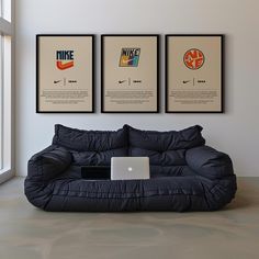 a couch with a laptop sitting on it in front of three framed posters above it