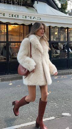 a woman is walking down the street wearing boots and a fur coat