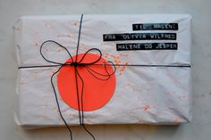 a wrapped present with an orange circle and black writing on the wrapping paper that says it all belong fra uliva wilfred malene do jesper