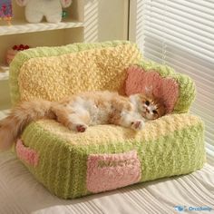 a cat laying on top of a green and pink chair