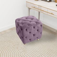 a purple foot stool sitting on top of a rug next to a white desk and mirror