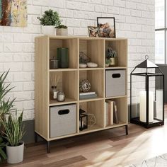 a living room with a white brick wall and wooden shelves filled with storage baskets, plants and books