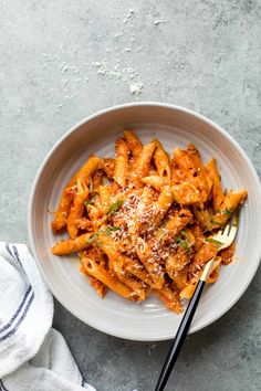 a white bowl filled with pasta and topped with parmesan cheese