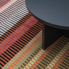 a black table sitting on top of a multi colored carpeted floor next to a coffee table