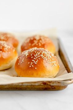 small rolls with sesame seeds sit on a plate