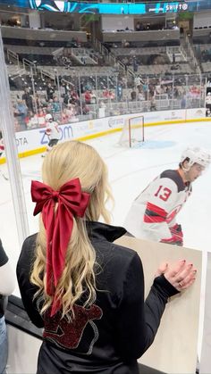 a woman wearing a red bow sitting in front of an ice hockey rink