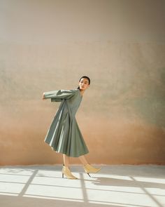 a woman in a green dress and heels posing for a photo with her arms outstretched