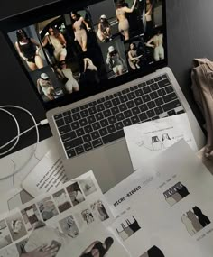 an open laptop computer sitting on top of a desk next to papers and other items