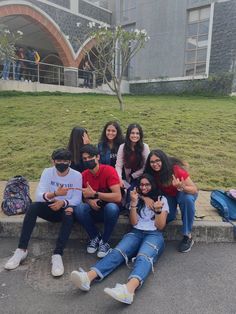 a group of young people sitting on top of a cement bench in front of a building