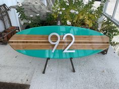 a surfboard with the number twenty two on it sitting in front of some potted plants