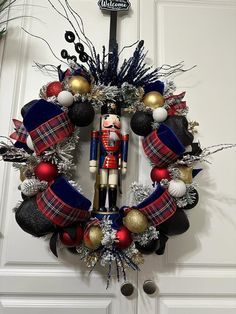 a wreath with a nutcracker and decorations hanging from it's front door