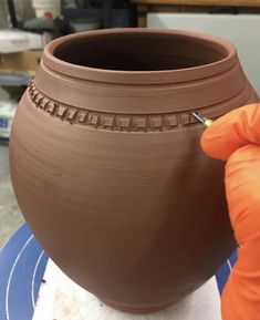 a person is painting a pot on a table