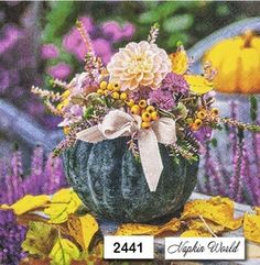 an image of a pumpkin with flowers in it on a table surrounded by purple and yellow leaves