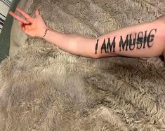 a woman's arm with the words i am music written on it and her hand