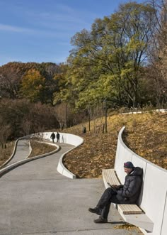 a man sitting on a bench next to a curved road