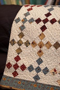 a close up of a quilt on top of a chair with a bookcase in the background