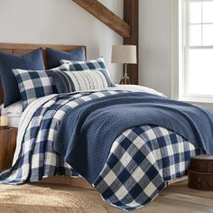 a blue and white plaid comforter set on a bed in a room with wood beams