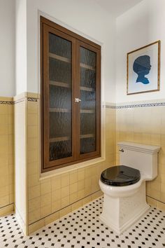 a bathroom with a toilet, cabinet and tiled floored walls is shown in this image