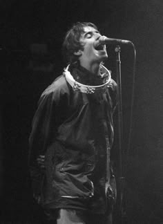 a black and white photo of a man singing into a microphone