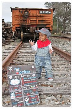 a little boy standing on train tracks with his hand in the air